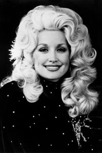 Black and White Photo of a woman smiling with luscious blond hair and a black dress with rhinestones
